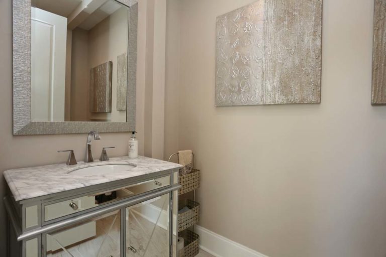 Powder room with marble countertop and mirrored cabinet doors.