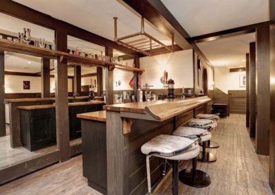 Bar with hardwood floors, counter with stools, rack for glassware.