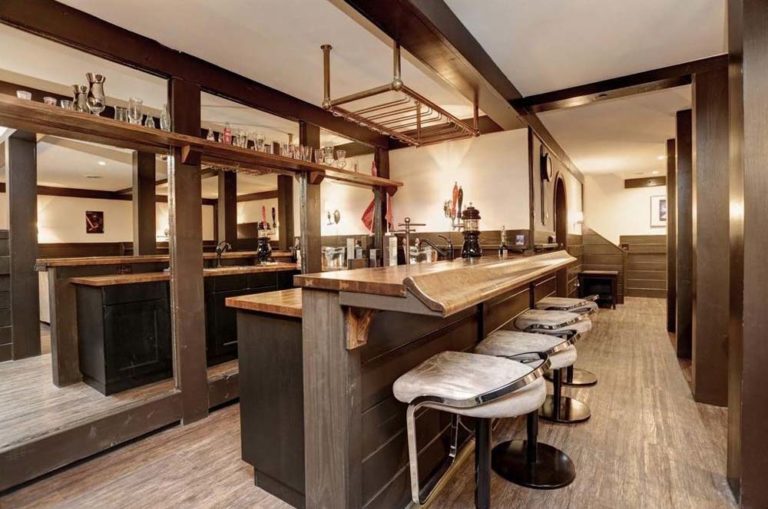 Bar with hardwood floors, counter with stools, rack for glassware.