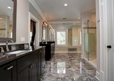 Master bathroom with large walk-in shower, marble tile floors, his and hers sinks, and mirrored walls.