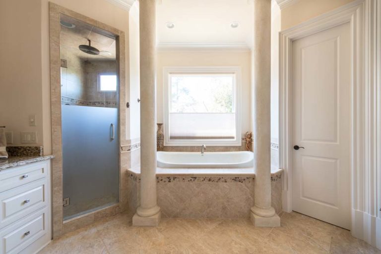 Bathroom with bathtub flanked by two columns, and walk-in shower.