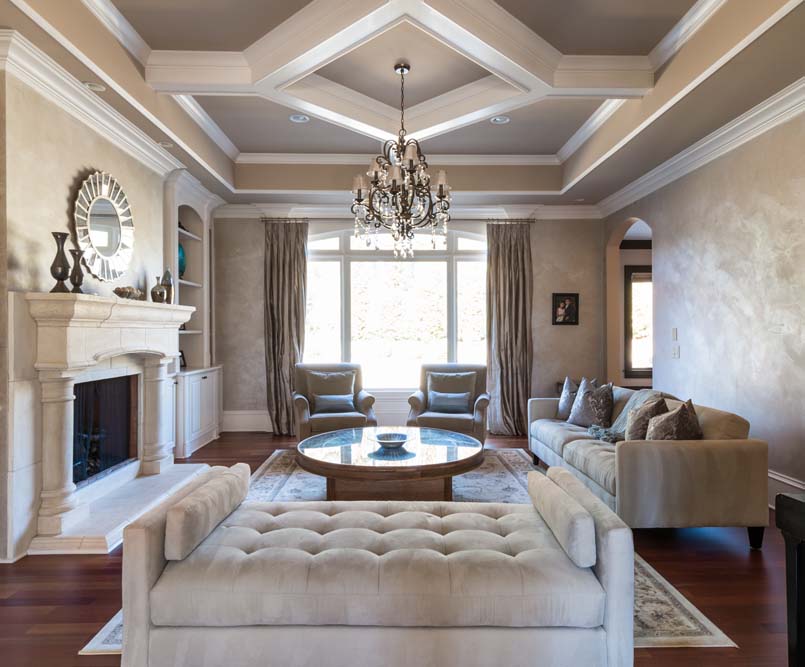 Living Room with custom tray ceiling, chandelier, fireplace, and large arched window.