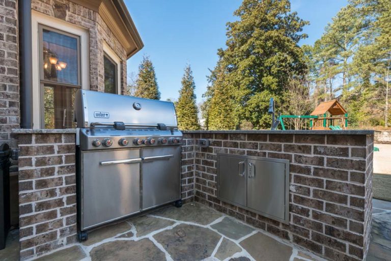 Outdoor grill in brick setting on stone patio.