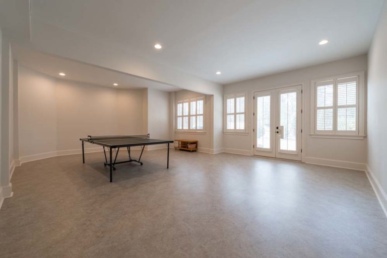 Large playroom with ping-pong table, several windows, and double doors to outside.