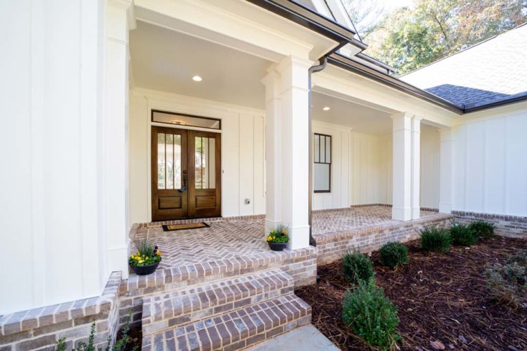 Brick front steps and covered porch with wood double front door